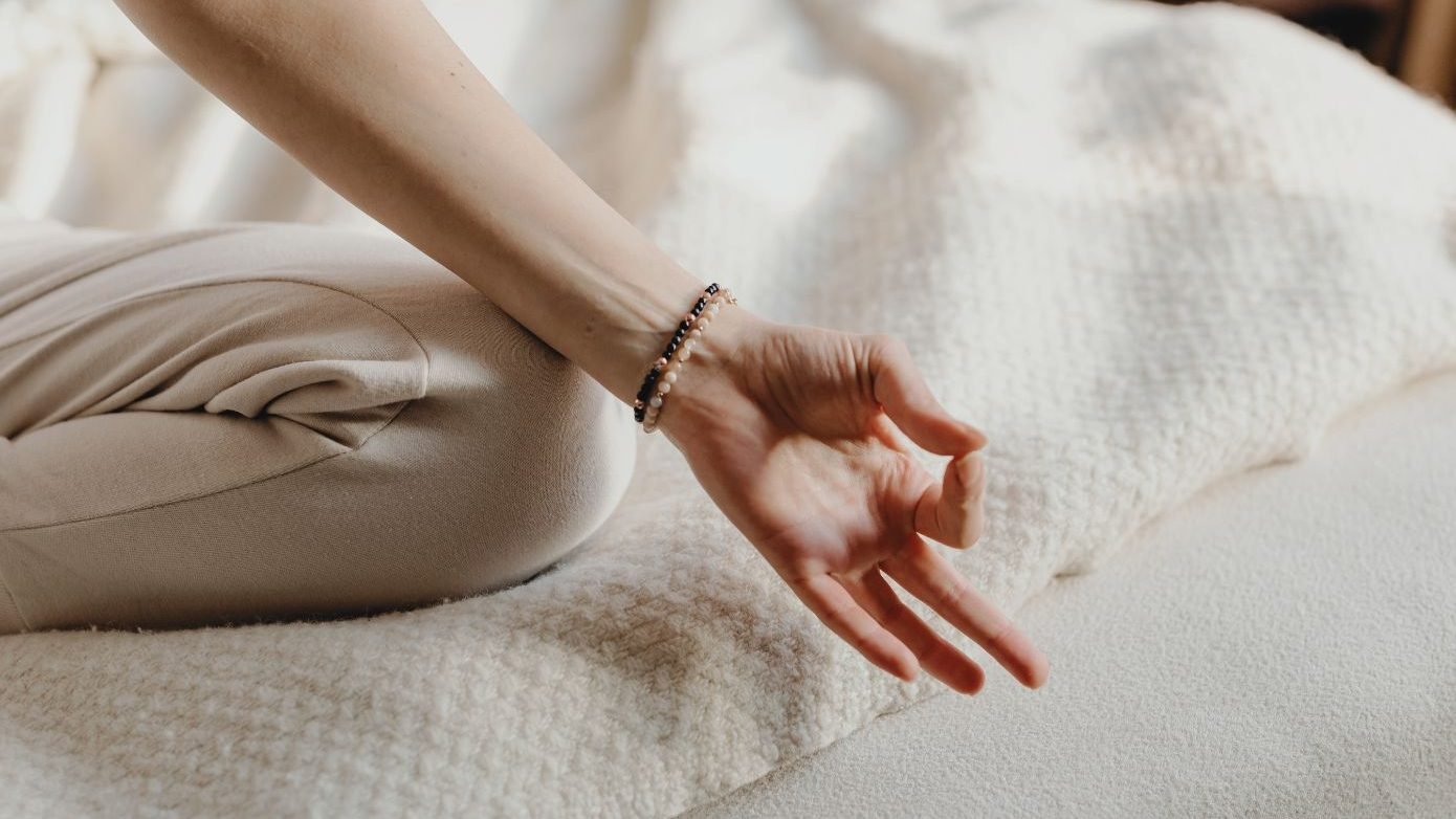 Hand of a woman doing om while practicing yoga. The image shows an example of mindful morning, as a strategy for living with intention and presence